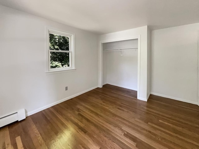 unfurnished bedroom with baseboard heating, a closet, baseboards, and wood finished floors