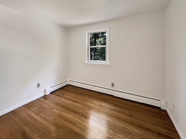 spare room featuring a baseboard radiator, wood finished floors, and baseboards