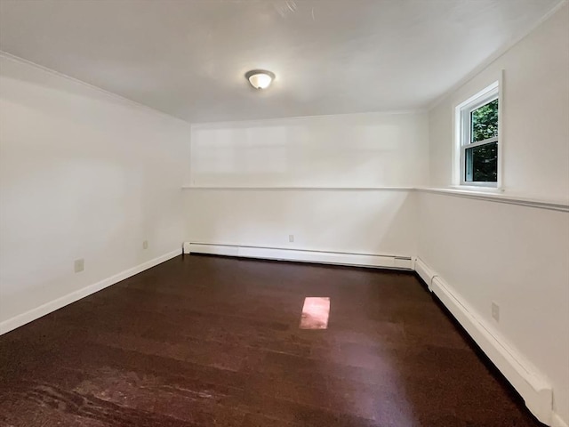 spare room with baseboard heating, wood finished floors, and baseboards