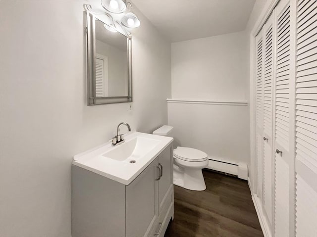 half bathroom featuring toilet, baseboard heating, wood finished floors, and vanity