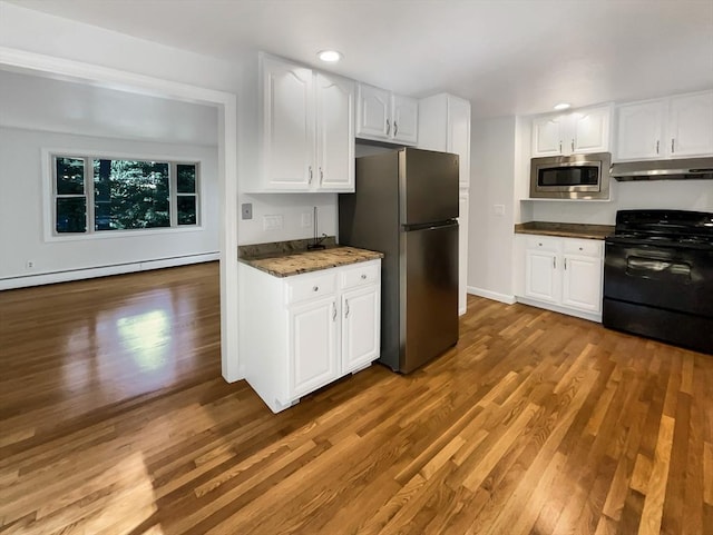 kitchen with light wood-type flooring, under cabinet range hood, white cabinetry, and appliances with stainless steel finishes