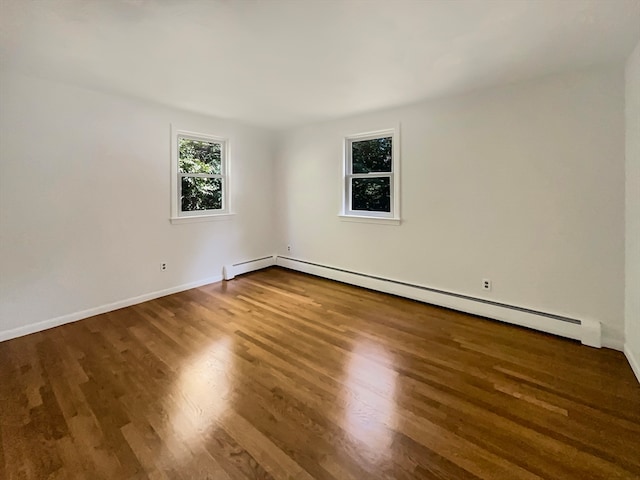 spare room featuring baseboard heating and dark hardwood / wood-style floors