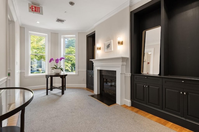 sitting room featuring baseboards, visible vents, ornamental molding, and a fireplace with flush hearth