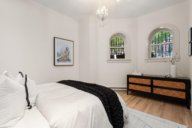 bedroom featuring a chandelier, baseboard heating, and wood finished floors