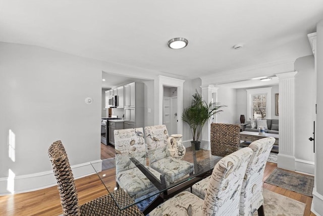 dining space with decorative columns and light wood-type flooring