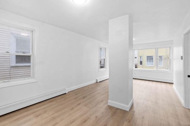 unfurnished room featuring a baseboard radiator and light wood-type flooring