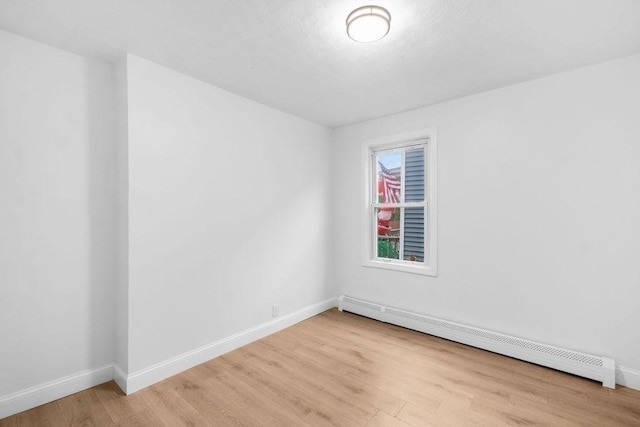 unfurnished room with light wood-type flooring and baseboard heating