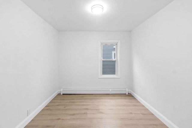 empty room with light hardwood / wood-style floors and a baseboard heating unit