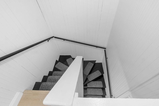 stairway featuring wood walls