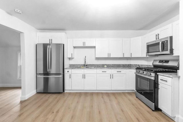 kitchen featuring white cabinets, sink, light stone counters, and stainless steel appliances