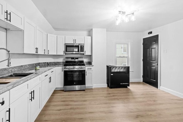 kitchen with white cabinetry, sink, stainless steel appliances, and light stone counters