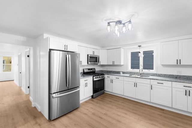 kitchen featuring sink, light hardwood / wood-style floors, light stone counters, white cabinetry, and stainless steel appliances