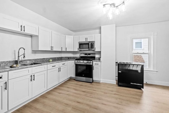 kitchen with sink, light stone countertops, light hardwood / wood-style floors, white cabinetry, and stainless steel appliances