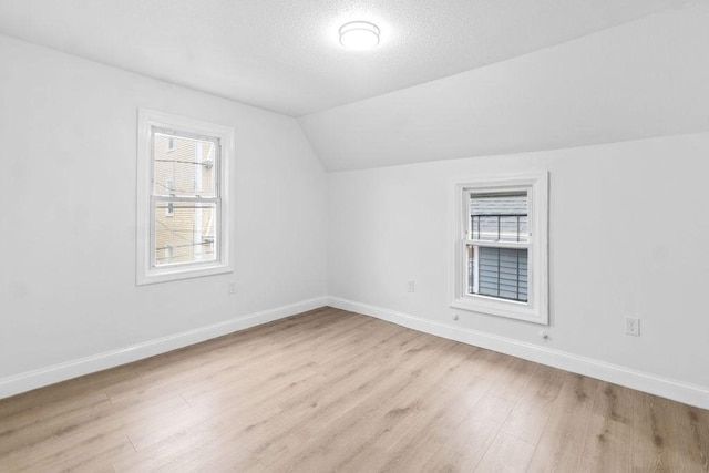 bonus room featuring a textured ceiling, light wood-type flooring, and vaulted ceiling