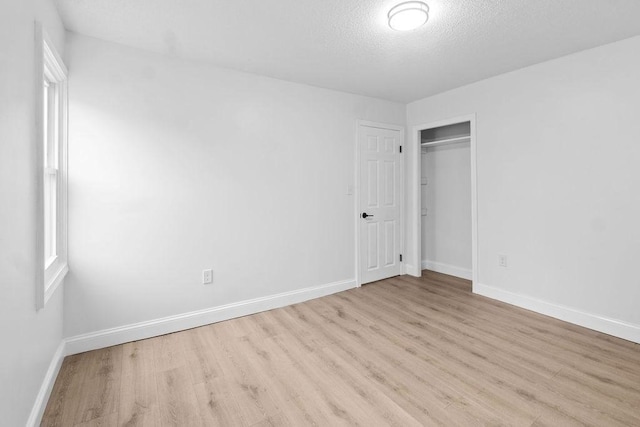 unfurnished bedroom with a closet, light hardwood / wood-style flooring, and a textured ceiling