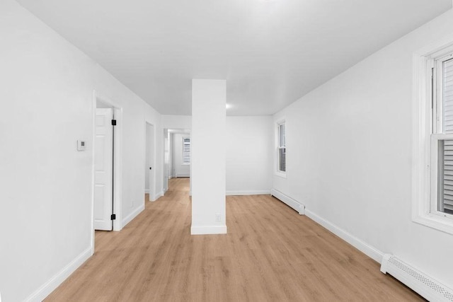 empty room featuring baseboard heating and light hardwood / wood-style flooring