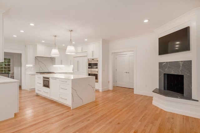 kitchen featuring light stone counters, light wood-style flooring, white cabinets, appliances with stainless steel finishes, and tasteful backsplash