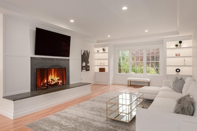 living room with a premium fireplace, wood finished floors, and built in features