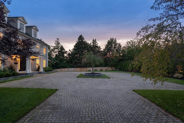 view of community featuring fence, decorative driveway, and a yard