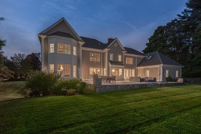 rear view of property featuring a chimney, an outdoor hangout area, a patio, and a yard