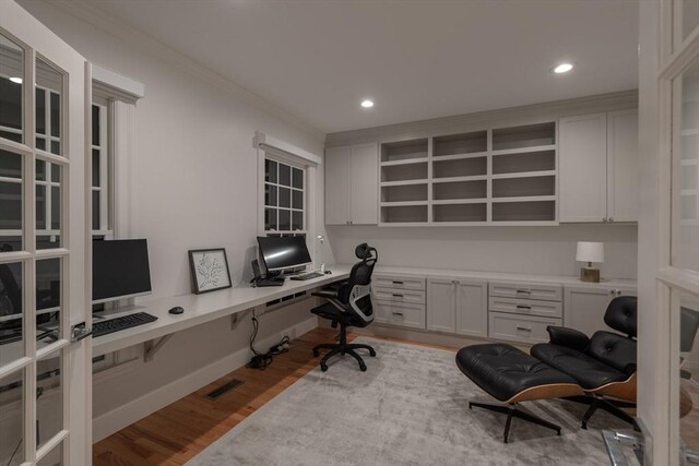 office with ornamental molding, built in desk, wood finished floors, and recessed lighting