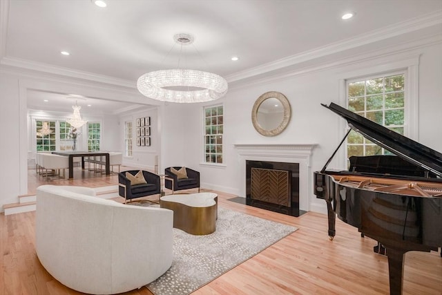 living room with a chandelier, a fireplace with flush hearth, light wood-style flooring, and a healthy amount of sunlight