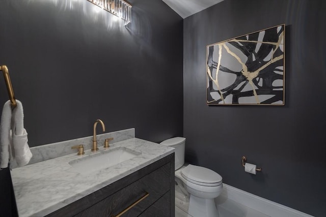 bathroom with toilet, baseboards, and vanity