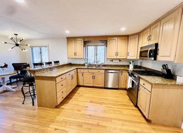 8 Tall Tree Way, Georgetown, MA 01833 - kitchen with appliances with stainless steel finishes, light brown cabinetry, a breakfast bar area, a peninsula, and light wood finished floors