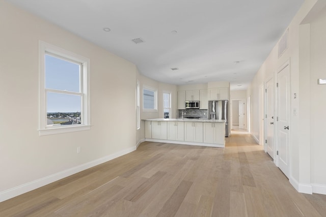 unfurnished living room with visible vents, baseboards, and light wood-style floors