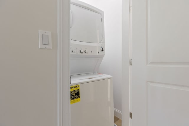 clothes washing area with stacked washer / dryer, laundry area, and baseboards