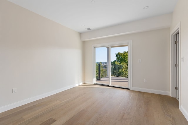 unfurnished room featuring light wood finished floors, visible vents, and baseboards