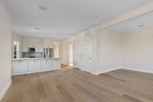 kitchen featuring stainless steel appliances, visible vents, open floor plan, and light countertops