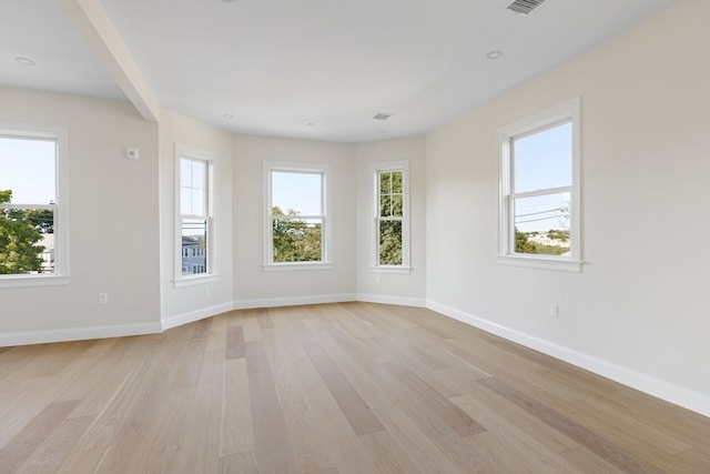 empty room featuring light wood-type flooring, plenty of natural light, and baseboards