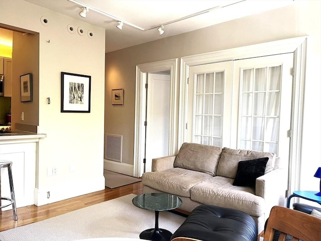 living area with rail lighting, wood finished floors, and visible vents