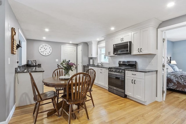 30 Millham St, Marlborough, MA 01752 - kitchen with gas stove, light wood-type flooring, white cabinets, backsplash, and a sink