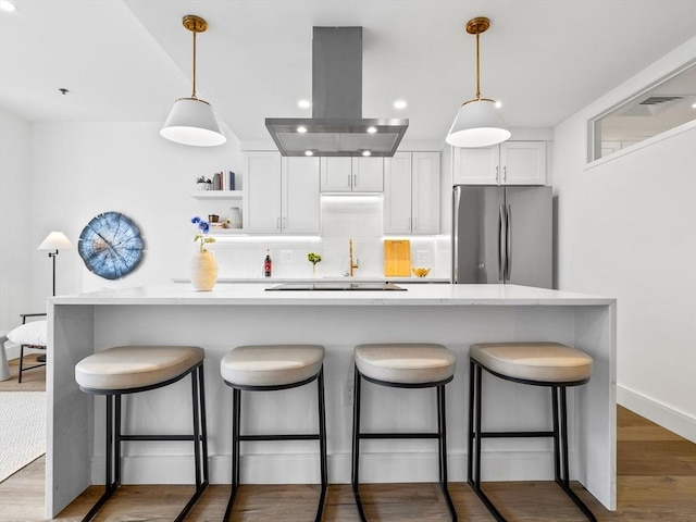 kitchen with freestanding refrigerator, light countertops, decorative backsplash, and island exhaust hood