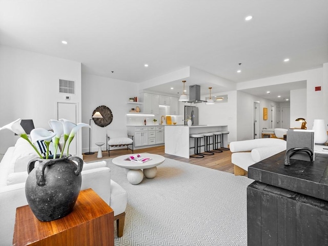 living area with recessed lighting, visible vents, and light wood-style floors