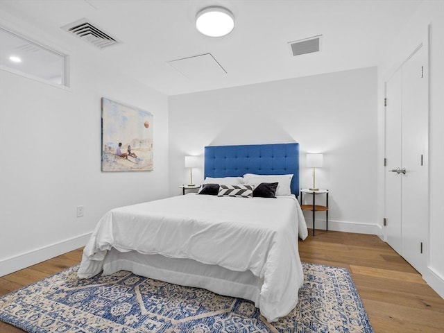 bedroom featuring baseboards, visible vents, and wood finished floors