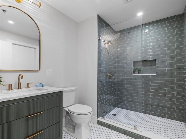 bathroom featuring toilet, tiled shower, and vanity