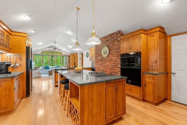 75 Haynes Rd, Sudbury, MA 01776 - kitchen with light wood-type flooring, black appliances, lofted ceiling, and brown cabinetry