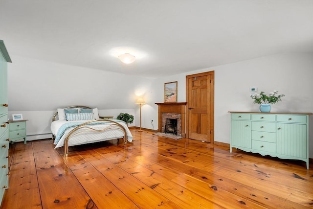 75 Haynes Rd, Sudbury, MA 01776 - bedroom with light wood finished floors, a brick fireplace, and a baseboard radiator