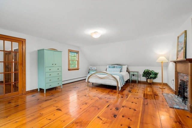 75 Haynes Rd, Sudbury, MA 01776 - bedroom with a baseboard heating unit, lofted ceiling, light wood-style flooring, a fireplace, and baseboards