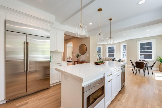 kitchen featuring arched walkways, white cabinets, built in appliances, recessed lighting, and light wood-style flooring