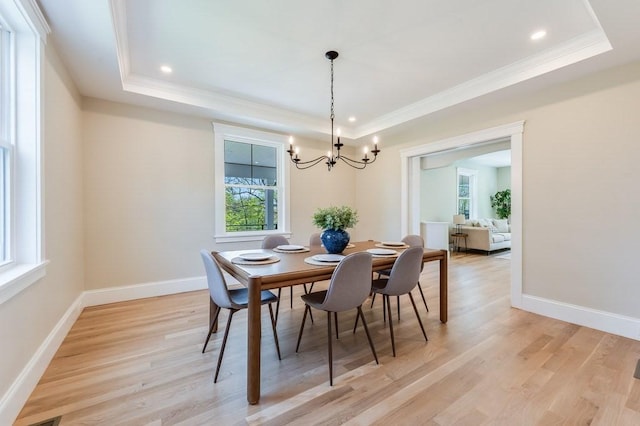 dining room with an inviting chandelier, ornamental molding, recessed lighting, light wood-type flooring, and a tray ceiling