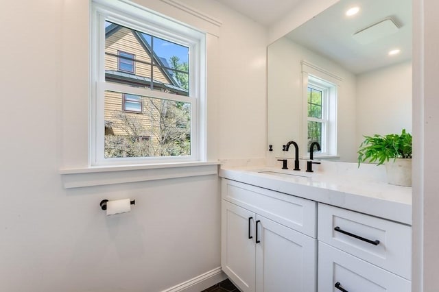 bathroom with vanity, baseboards, recessed lighting, and a wealth of natural light