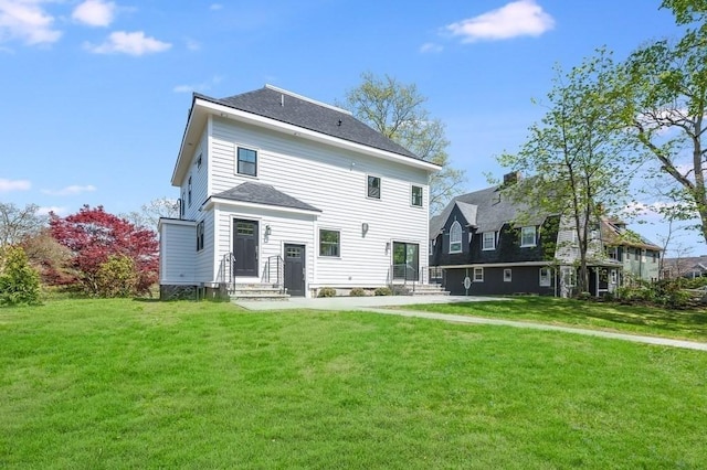 back of property with a shingled roof and a yard