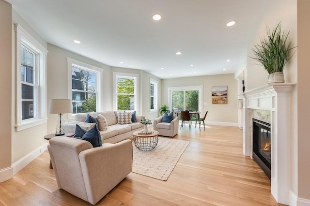 living room featuring baseboards, light wood-style flooring, and a fireplace