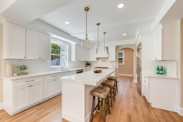 kitchen featuring a breakfast bar area, arched walkways, a sink, and light wood-style flooring