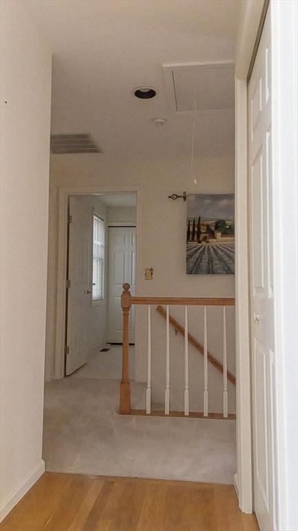 7 Brewster Ln Unit 7, Acton, MA 01720 - hall with attic access, visible vents, wood finished floors, baseboards, and an upstairs landing