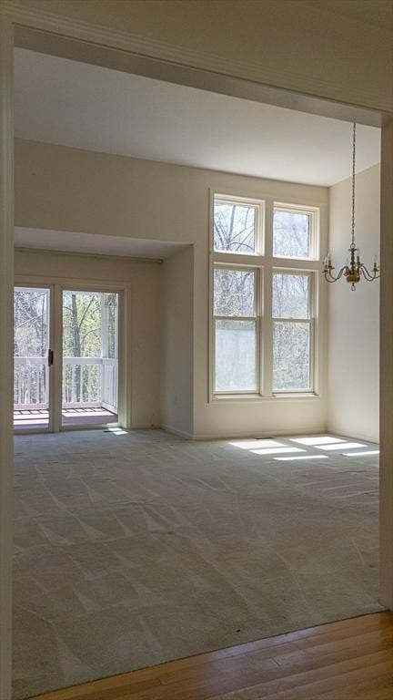 7 Brewster Ln Unit 7, Acton, MA 01720 - carpeted empty room featuring plenty of natural light, wood finished floors, and a chandelier